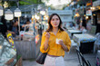 © Laingzaifa - Asian women enjoy delicious street food at night markets, smiling throughout their vacation, exploring the city's culture, vibrant lights, and fun-filled adventures.