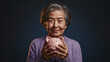 © bephoto - 夕方の柔らかな光の中で貯金箱を抱く高齢の日本人女性のライフスタイル