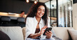 © EineroLens25/peopleimages.com - Cellphone, smile and woman on sofa in home with networking, communication or social media online. Happy, phone and female person reading blog with celebrity gossip on mobile app in living room.