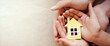 © GDShahid - Caring hands gently holding a small paper house symbolizing family protection and home security concept