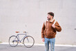 © Oscar - Young man standing with bicycle enjoying urban lifestyle