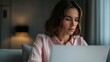 © Intelligent Horizons - A focused woman is deeply engaged in working on her laptop her expression thoughtful in a cozy dimly lit room suggesting remote work or study in the evening