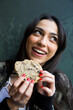 © Westend61 - Smiling woman looking sideways and eating cookie
