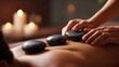 © by.anastasiya - Hot stone massage on woman back with therapist hands and candles in spa interior.