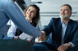 © opolja - Happy businessmen shaking hands at group board meeting