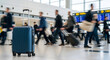 © ShutterBG - Blue Suitcase in Airport Terminal with Blurred Travelers