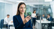 © Kaluya Stock - Businesswoman in a modern office uses facial recognition technology on her smartphone. A green biometric scan graphic and checkmark overlay her face as she looks at the phone