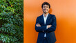 © ADDICTIVE STOCK - Confident professional smiling against orange wall