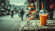 © DadGenX_Pic - Thai milk tea in plastic cup on rustic table, urban street