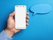 © AIHUN - Hand holding smartphone with blank screen next to speech bubble