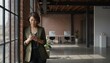 © GodNopparat - Modern Office Moment: A composed individual stands beside a large window, engrossed in their smart phone, embodying modern professional life, innovation and a comfortable working environment.