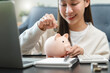 © Pormezz - Close-up hand of young woman putting  a coin into piggy bank.