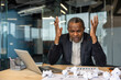 © Liubomir - Mature businessman stressed at his desk, clutching his head over a laptop and crumpled documents, facing a challenging project, tight deadline and financial pressure