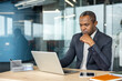 © Liubomir - Professional man thinking deeply and concentrating on his work, sitting at an office desk with a laptop and smartphone, reflecting focused attention in a corporate setting