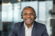 © Liubomir - Professional african american man wearing a headset with a microphone, smiling while working in an office environment, focused on providing excellent customer service and communication