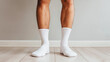 © Bonsales - Legs of a person wearing white socks standing on a wooden floor, representing domestic comfort and simplicity