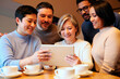 © Mediaphotos - Group of adult woman, adult man, young Black man, young woman and young man gathering around tablet, smiling and looking at screen