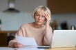 © Andrii Zastrozhnov - Elderly caucasian woman reviewing documents with laptop at home