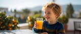 Young boy smiling while holding a glass of orange juice outdoors