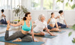 © JackF - Adult woman doing yoga on mat in group in fitness studio