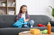 © New Africa - Girl packing her backpack for school on sofa at home. Space for text