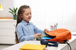 © New Africa - Girl packing her backpack for school at desk indoors. Space for text