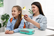 © New Africa - Mother and daughter packing backpack for school at desk indoors