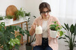 © New Africa - Woman watering beautiful potted houseplant at home