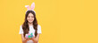 © Olena - smiling child in bunny ears hold eggs on yellow background. Easter child horizontal poster. Web banner header of bunny kid, copy space.