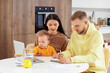 © Pixel-Shot - Young couple with their baby planning budget at table in kitchen