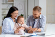 © Pixel-Shot - Young couple with their baby putting coin into piggy bank at home. Budget concept