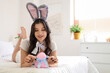 © Pixel-Shot - Sexy young woman in bunny costume with Easter egg lying on bed at home