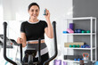 © Pixel-Shot - Sporty young woman with inhaler on exercising bike in gym