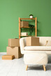 © Pixel-Shot - Sofa with cardboard boxes and pouf in living room on moving day