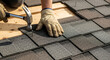© Ima - A worker aligning asphalt roof shingles and securing them with roofing nails closeup shot