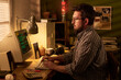© pressmaster - Caucasian middle aged man with beard sitting at desk typing on vintage computer monitor in home office setting, surrounded by retro technology and office supplies, focused on screen