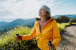 © oneinchpunch - Active senior woman hiking on outdoor trail using trekking poles