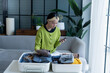 © Charlie's - Happy asian Woman doing checklist for packing suitcase before holidays trip.