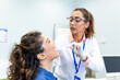 © Graphicroyalty - Throat examination and medical checkup. Female doctor using tongue depressor on patient, Healthcare and Medicine concept. Professional physician checking sore throat of young woman at clinic.