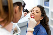 © Graphicroyalty - ENT specialist throat examination. Doctor using headlamp to check patient's throat, Healthcare and Medicine concept. Otolaryngologist inspecting mouth and tonsils of young woman in medical clinic.