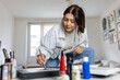 © Graphicroyalty - Creative female artist painting in her light-filled home studio, focused young woman using a palette and brush on canvas, authentic artist lifestyle, hobby and small business concept at home.