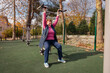 © _KUBE_ - Older Caucasian woman using outdoor fitness machines in a green park. Physical activity, health, and long life in retirement.