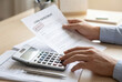 © ABmachine - Person calculating while holding an approved loan agreement document