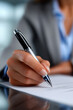 © Mselected - Hand holds pen and writes on paper in office setting during day