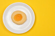 © nahhan - A top down view of a single golden baked round butter cookie filled with sweet yellow lemon curd served on a small white ceramic plate over a bright yellow surface