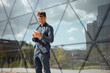 © ADDICTIVE STOCK - Man using smartphone outside modern office building