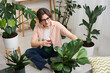 © New Africa - Woman spraying beautiful potted houseplant with water indoors