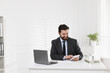 © New Africa - Businessman working at table near white wall indoors, space for text