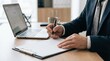 © Chanoknan - Business professional writing notes on clipboard with laptop and coffee cup on desk in modern office setting for workflow optimization and administrative management analytics outcomes