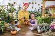 © sofiko14 - A mother and daughter enjoy a gardening activity, surrounded by lush greenery and a variety of potted plants